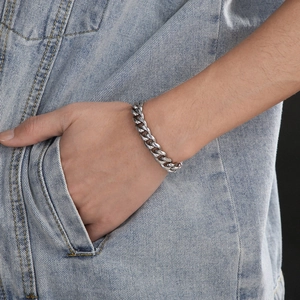 Polished silver stainless steel Cuban link bracelet shown on model with denim jacket