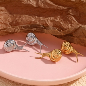 Macro shot of 18K gold and silver plated snail earrings on a decorative tray