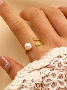 Close-up of golden adjustable ring with white pearl and sparkling zircon leaves