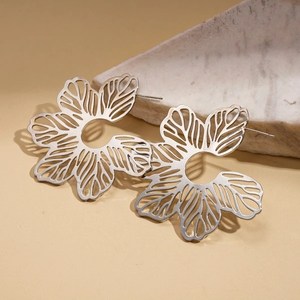 Detail of silver hollow petal earrings resting on a white marble stone base