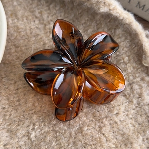 Detail of vintage leopard print flower hair claw clip on soft plush background