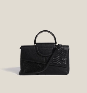 Detail view of black clutch with lychee and crocodile leather textures and top handle