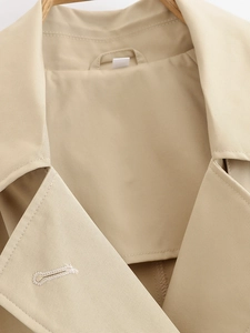 Detailed close-up of beige trench coat collar and lapel with fine twill texture stitching