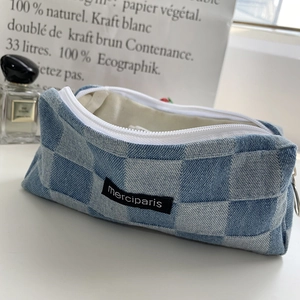 Detailed macro view of the blue plaid denim pouch with merciparis tag and white zipper