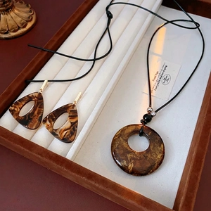 Retro leopard print resin jewelry set featuring a round pendant necklace and triangle earrings