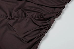 Detail of ruched chocolate brown fabric with elegant draped pleats on women dress