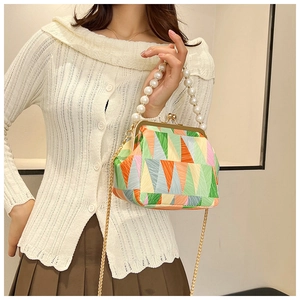 Detail of color-block geometric mini bag featuring pearl handle and gold chain strap