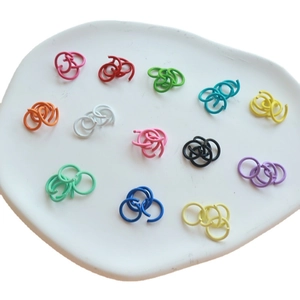 Colorful painted metal jump rings for DIY keychains displayed on a ceramic tray