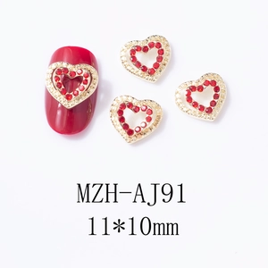 Vue macro du bijou d'ongle coeur évidé 11x10mm avec strass rouges sur base en alliage doré
