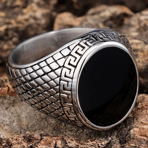 Macro shot of vintage stainless steel ring with black round stone and Greek key pattern
