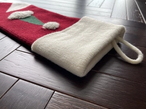 Close-up of red and white knitted Christmas stocking with textured patterns on wooden floor