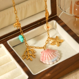 Detail of gold starfish and pink shell pendants on ocean theme necklace in a jewelry box