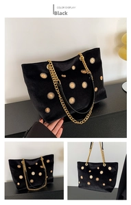 Detail of black velvet tote bag featuring golden sunflower studs and chain strap