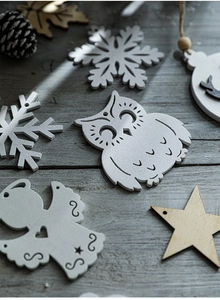 Close-up of wooden Christmas ornaments featuring snowflake and angel shapes on wood surface