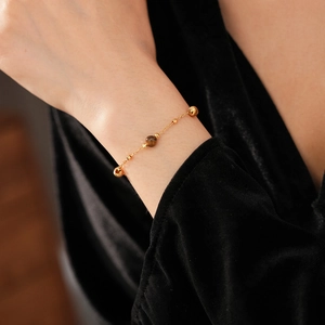 Close-up of gold-plated bracelet with brown tiger eye stone and metallic beads