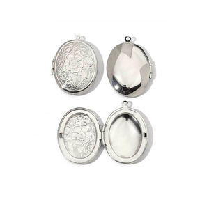Detail of oval silver stainless steel locket showing engraved pattern and inner photo compartment