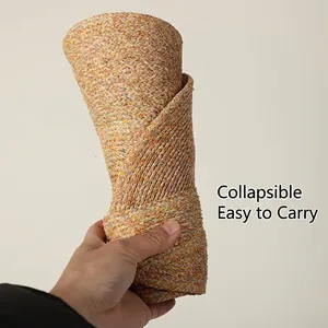 Foldable raffia straw sun hat being rolled up to show portable and flexible design