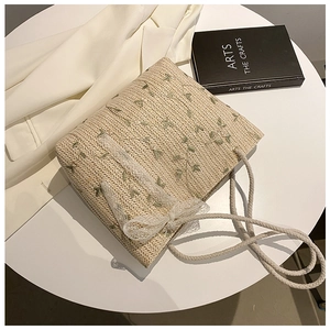 Straw tote bag with green floral embroidery, lace bow detail and thick rope handles