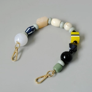 Macro detail of multi-colored resin beads handbag chain with golden metal lobster clasps