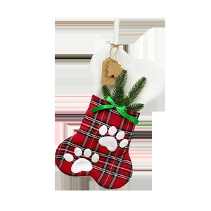 Detail of bone-shaped plaid Christmas stocking with paw prints and green ribbon bow