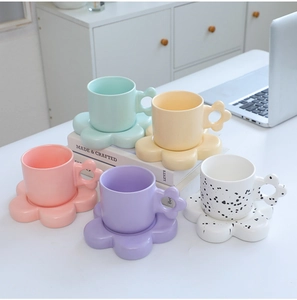 Detailed view of colorful flower-shaped ceramic mugs and matching saucers set