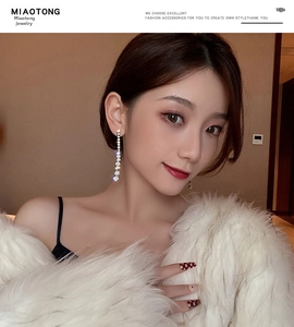 Detail of luxury long tassel rhinestone earrings worn by a model in a fur coat