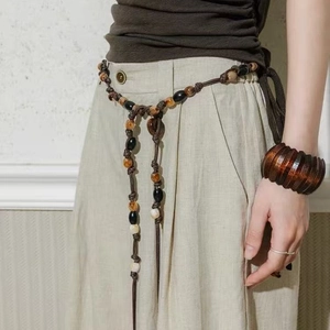 Bohemian woven waist chain with obsidian beads and vintage wood bracelet on earthy tone outfit
