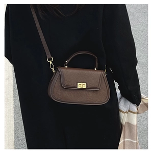 Vue de dos d'un mannequin portant un sac en cuir marron foncé avec fermoir doré