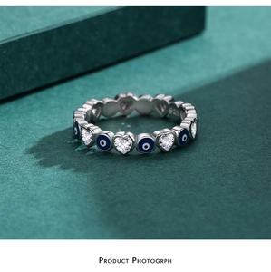 Macro shot of S925 sterling silver evil eye ring with heart-shaped crystal on green background