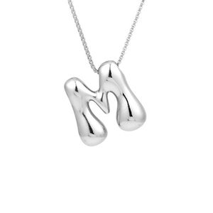 Macro detail of puffy silver 18K letter M bubble pendant on a polished link chain