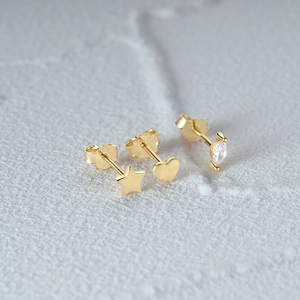 Close-up of S925 silver stamp on gold heart and star earrings with cubic zirconia