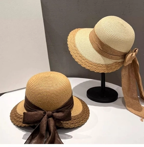 Detail of straw sun hats with elegant large ribbon bows in khaki and beige colors