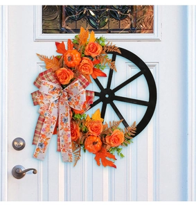 Detail of autumn wreath with orange roses, mini pumpkins, and a plaid bow on a black wheel