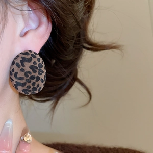 Close-up of a large oval leopard print flocked earring on a model for a stylish look