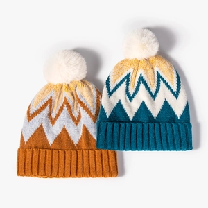 Chic knit beanies in orange and teal with zigzag patterns and fluffy pom-poms