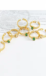 Detail of gold-plated twisted rings featuring green and clear square zircon stones