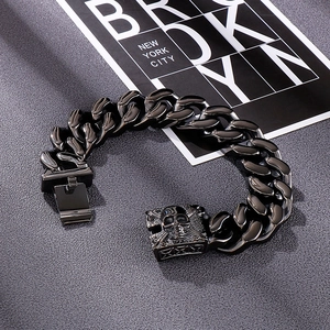 Close-up of gunmetal Cuban link chain bracelet with detailed skull push-lock clasp