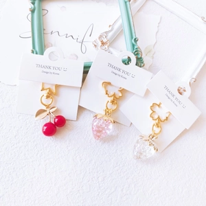 Colorful strawberry and cherry keychains with gold metal hardware on white card