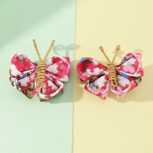 Detail view of handmade fabric butterfly clips with pink floral patterns and gold wire