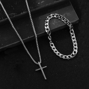 Close-up of men's silver cross pendant necklace and cuban link bracelet jewelry set