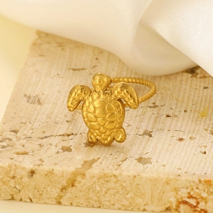 Dettaglio macro di un anello a tartaruga dorato regolabile su superficie in pietra naturale