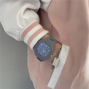 Macro shot of a square blue dial watch with grey silicone strap and silver bracelet on wrist