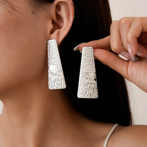 Exaggerated geometric silver trapezoid earrings with textured finish on female model