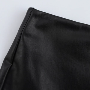 Close-up of black faux leather texture and side slit stitching on minimalist A-line shorts