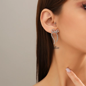 Close-up of elegant gold bow earrings with pavé crystals on a model's ear lobe