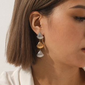 Three-tier shell-shaped earrings in two-tone gold and silver steel on a model