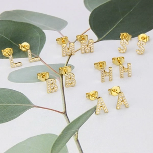 Detailed close-up of gold-plated letter earrings inlaid with sparkling white zircon stones