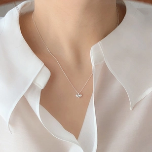 Close-up of minimalist S925 silver heart necklace worn by a model on a white background