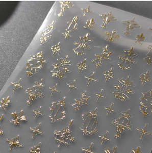 Macro detail of gold foil nail stickers featuring zodiac signs and sparkling star motifs