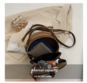 Detail view of brown circular crossbody bag showing internal compartments and storage